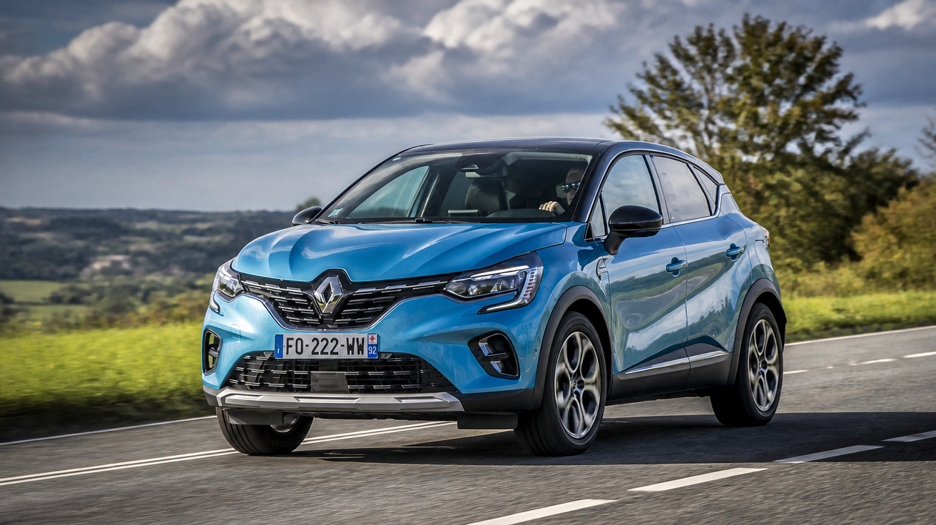 Blue Renault Captur SUV driving on a rural road under a cloudy sky.