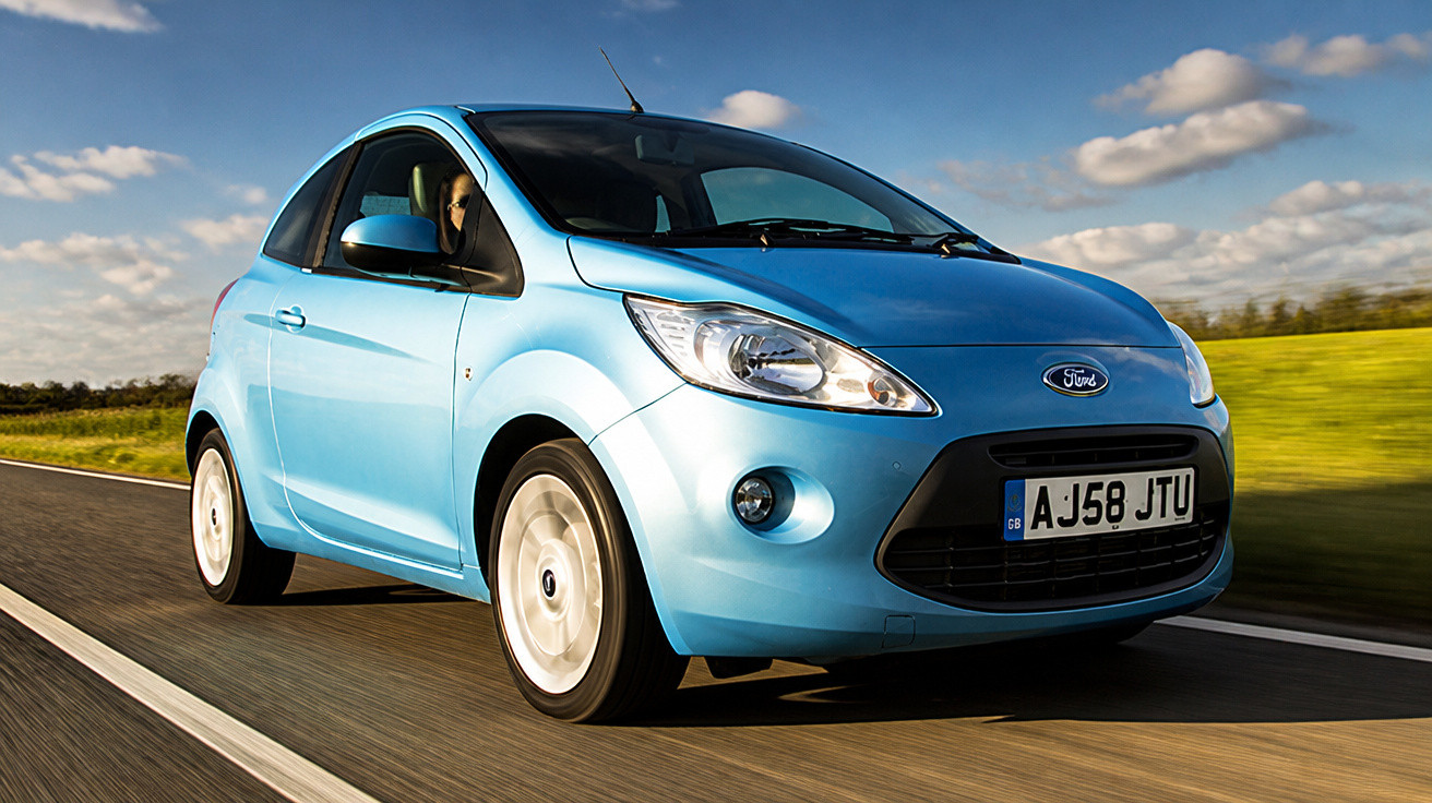 Blue Ford compact car driving on a countryside road under a partly cloudy sky.