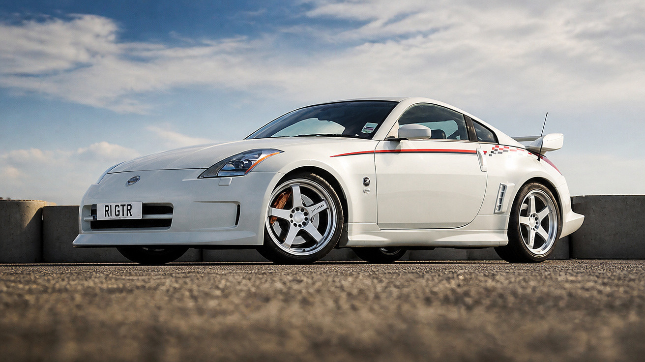 White Nissan 350Z sports car with silver alloy wheels parked on tarmac under a partly cloudy sky.