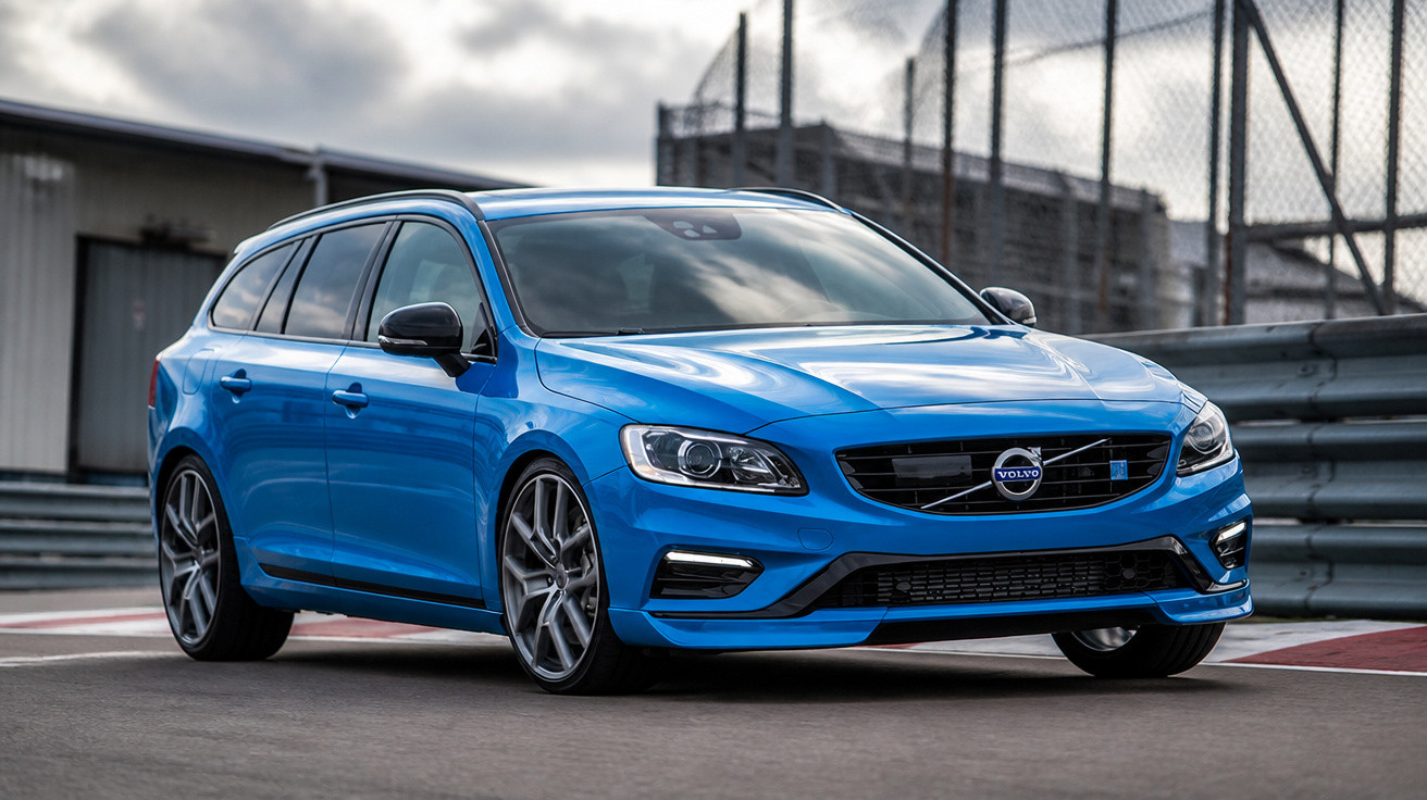 Blue Volvo station wagon parked on a race track with a cloudy sky in the background.