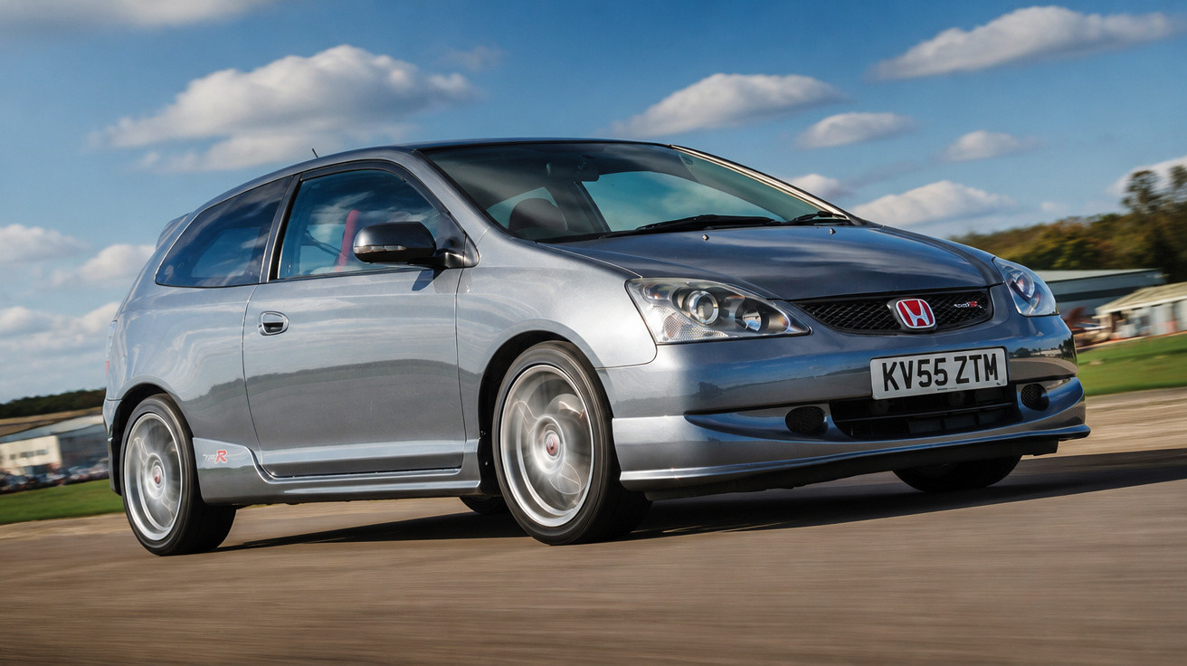 Silver Honda Civic Type R hatchback driving on a road under a blue sky with clouds.