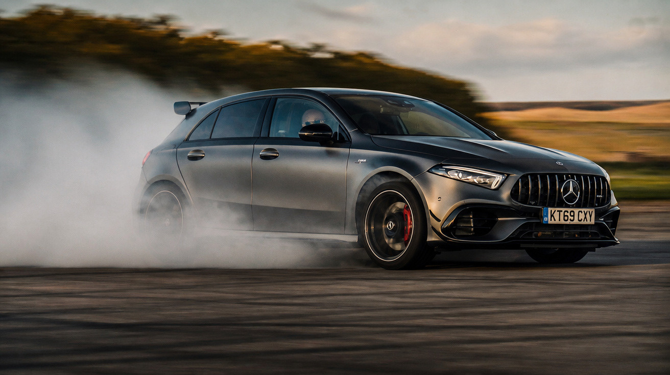 Matte black Mercedes-Benz hatchback drifting on a track, creating smoke from the rear tyres.
