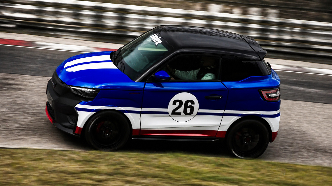 Blue and white number 26 racing car with black roof driving on a race track with blurred background